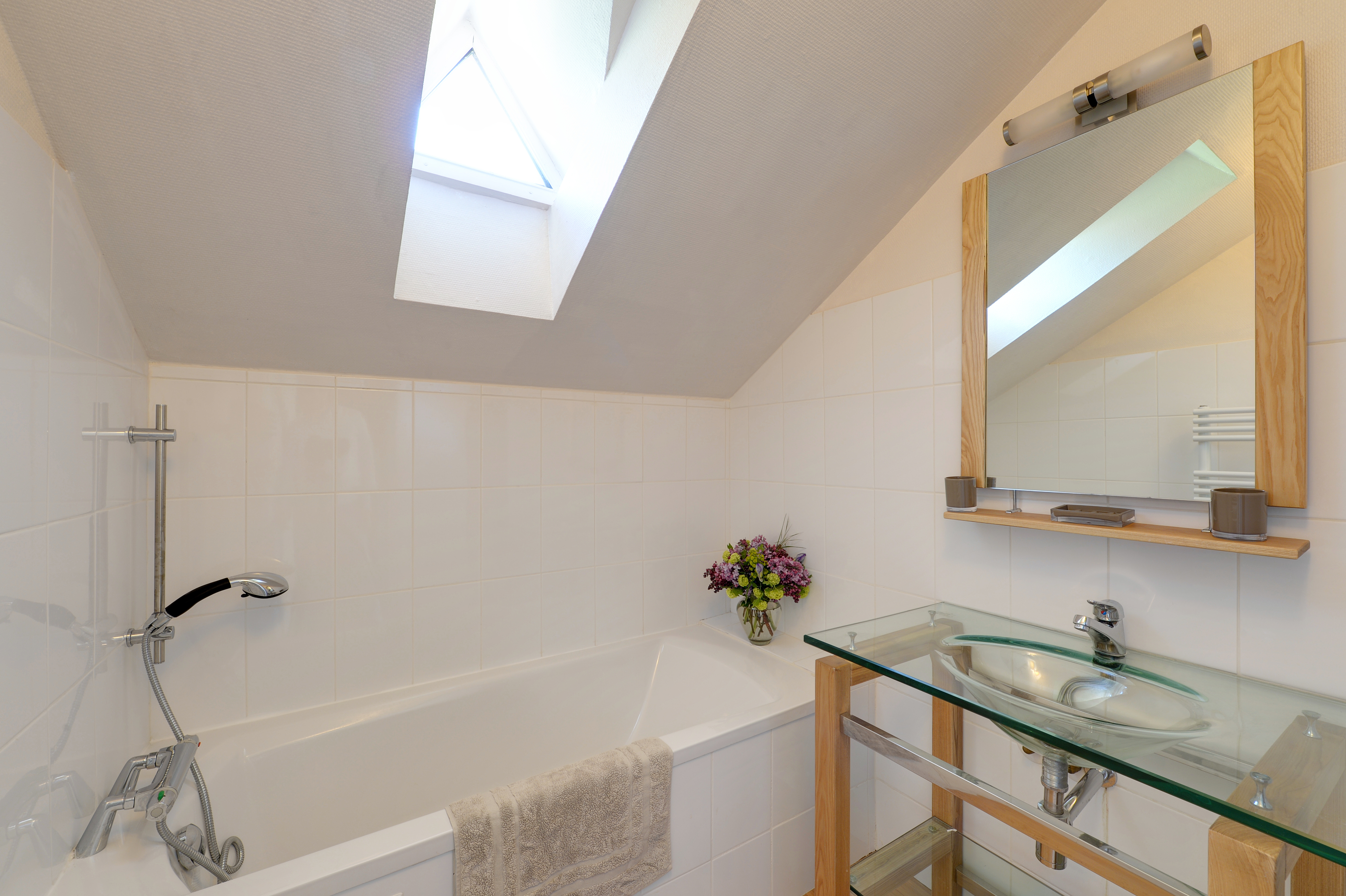 Salle de bain moderne avec baignoire et lumière naturelle venant du velux.